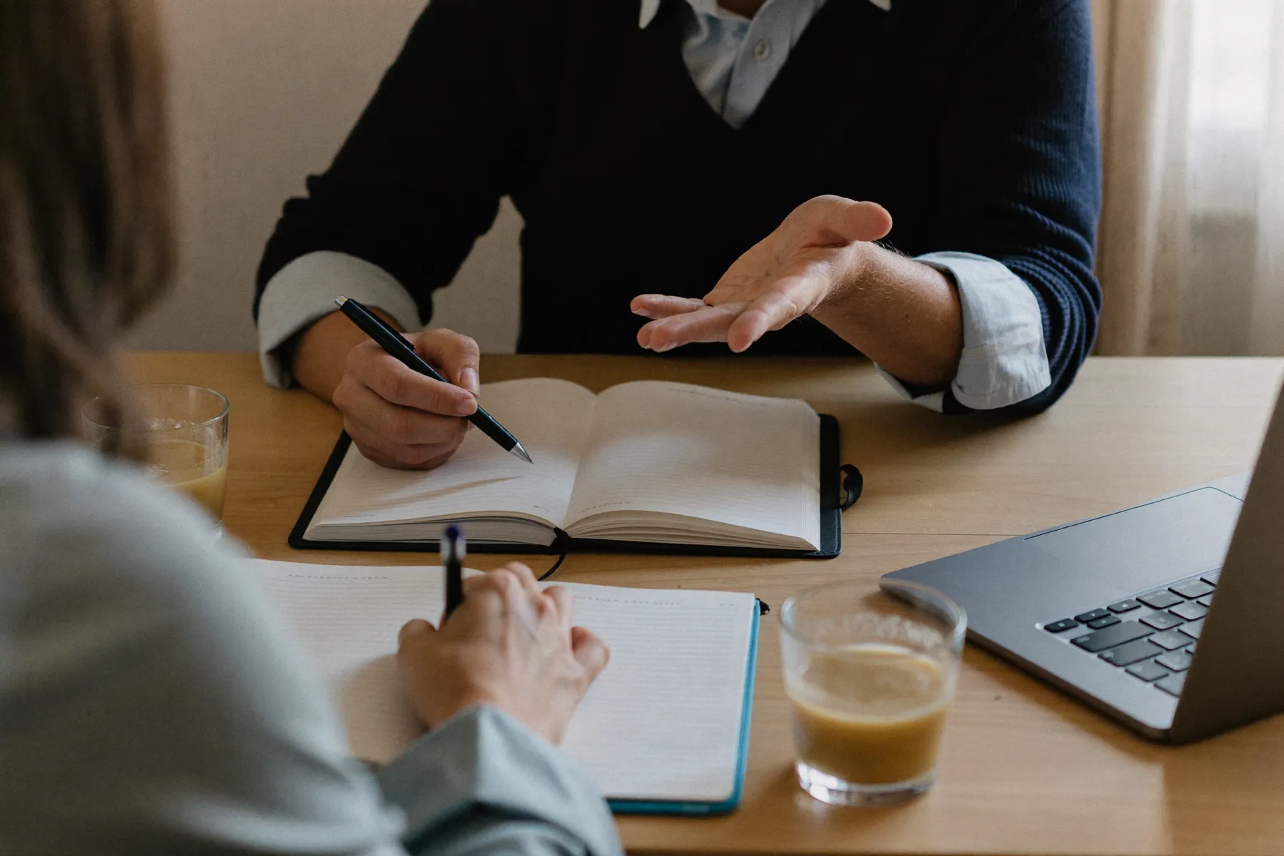 Two people in a calm feedback conversation over notebooks and chai