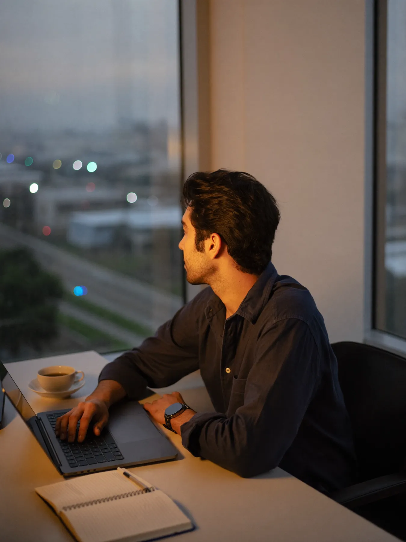 A founder sitting by an office window in the evening, thinking